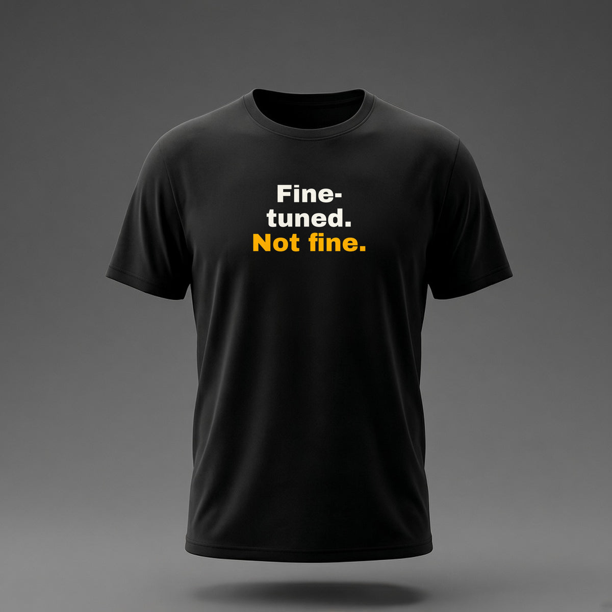 Front view: Black t-shirt floating on a grey background with 'Fine-tuned. Not fine.' in three heavy lines printed across the chest in off-white and amber.