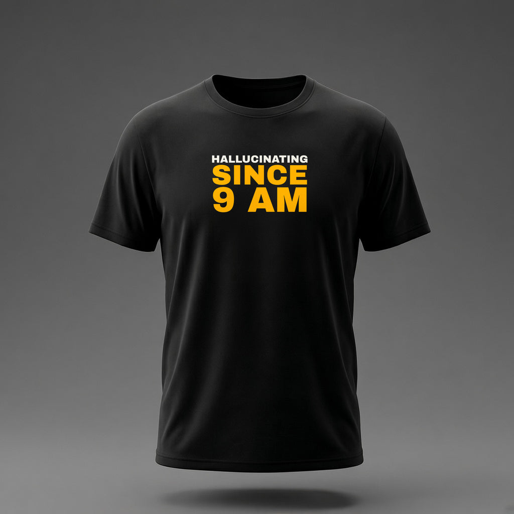 Front view: Black t-shirt floating on a grey background with 'Hallucinating since 9 AM' as a justified stack printed across the chest in off-white and amber.