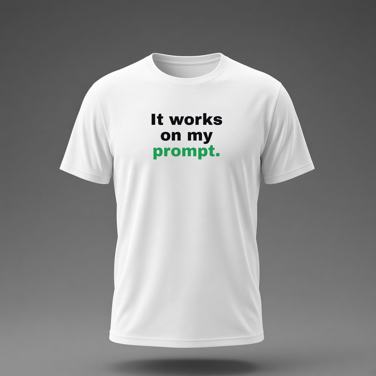 Front view: White t-shirt floating on a grey background with 'It works on my prompt.' in three heavy lines printed across the chest in black and dark green.