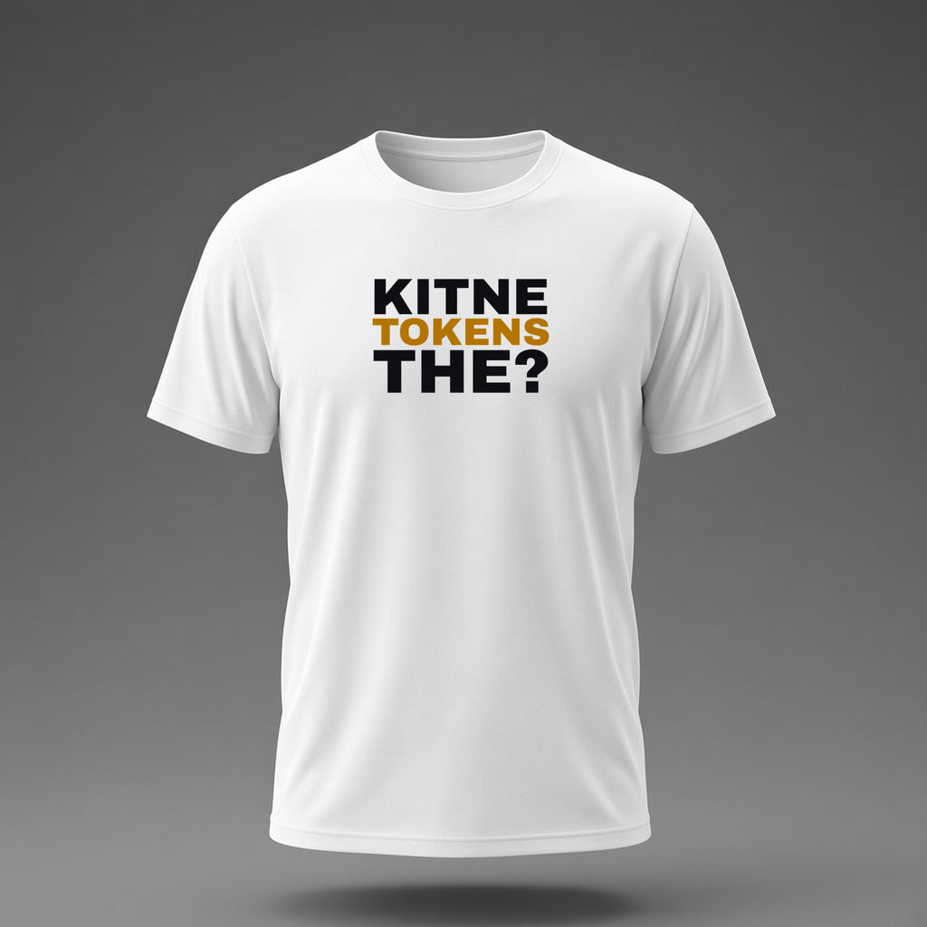 Front view: White t-shirt floating on a grey background with 'Kitne tokens the?' as a justified heavy stack printed across the chest in black and dark amber.