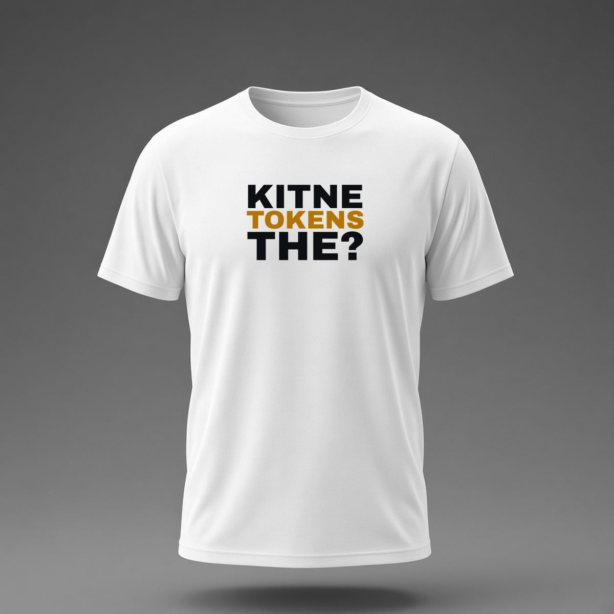 Front view: White t-shirt floating on a grey background with 'Kitne tokens the?' as a justified heavy stack printed across the chest in black and dark amber.