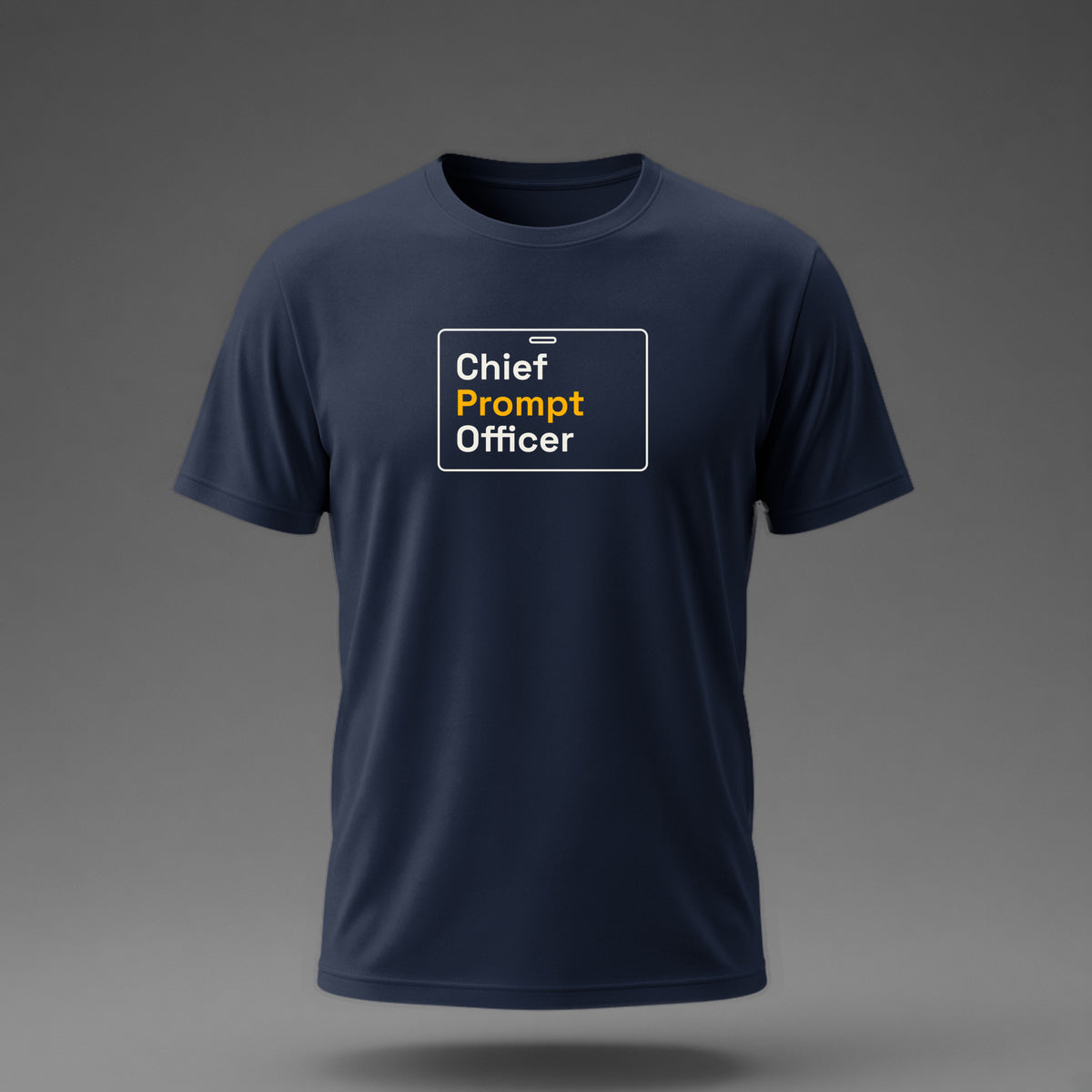 Front view: Navy t-shirt floating on a grey background with 'Chief Prompt Officer' on an ID-badge outline printed across the chest in off-white and amber.