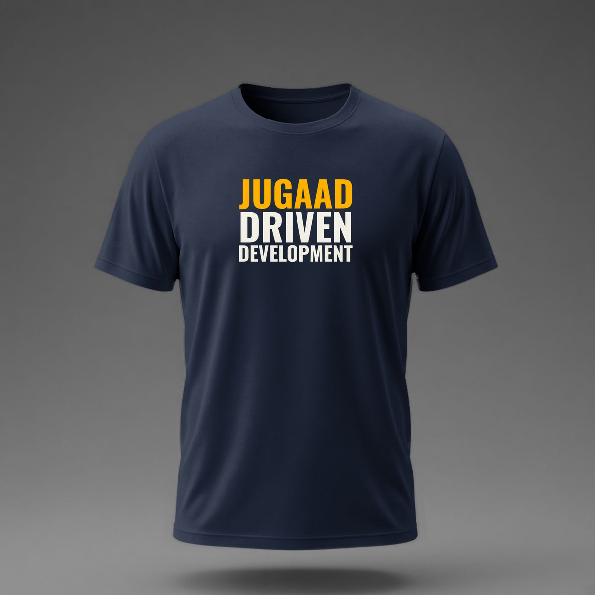 Front view: Navy t-shirt floating on a grey background with 'Jugaad Driven Development' as a justified stack printed across the chest in off-white and amber.