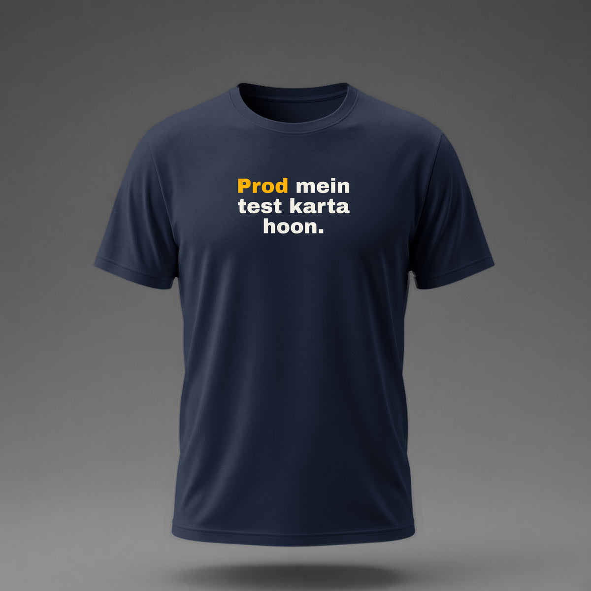 Front view: Navy t-shirt floating on a grey background with 'Prod mein test karta hoon.' in three heavy lines printed across the chest in off-white and amber.