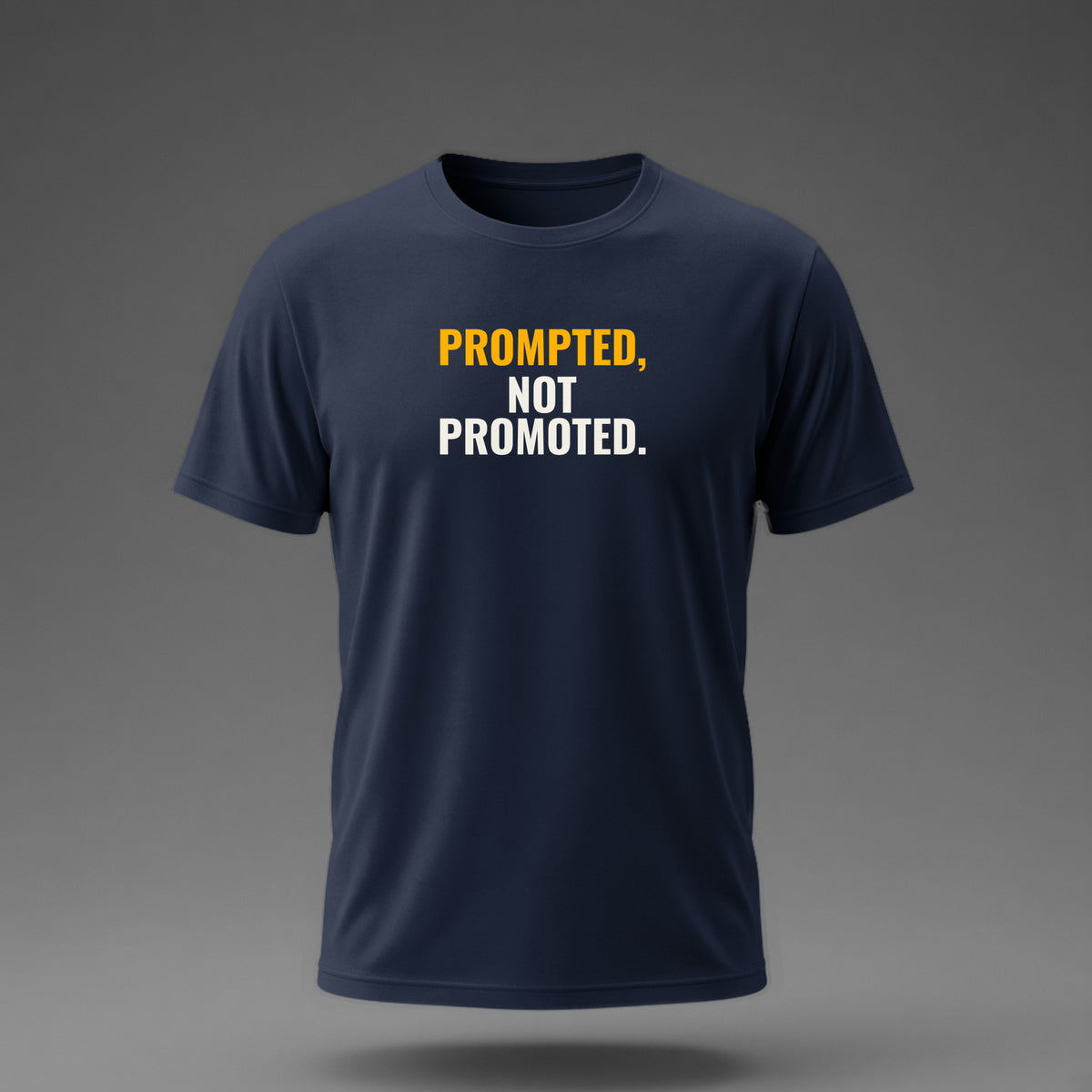 Front view: Navy t-shirt floating on a grey background with 'Prompted, not promoted.' as a heavy condensed stack printed across the chest in off-white and amber.