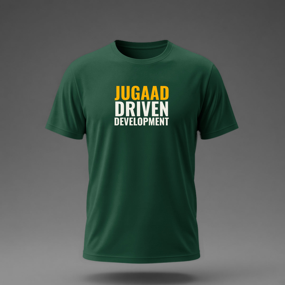 Front view: Bottle Green t-shirt floating on a grey background with 'Jugaad Driven Development' as a justified stack printed across the chest in off-white and amber.