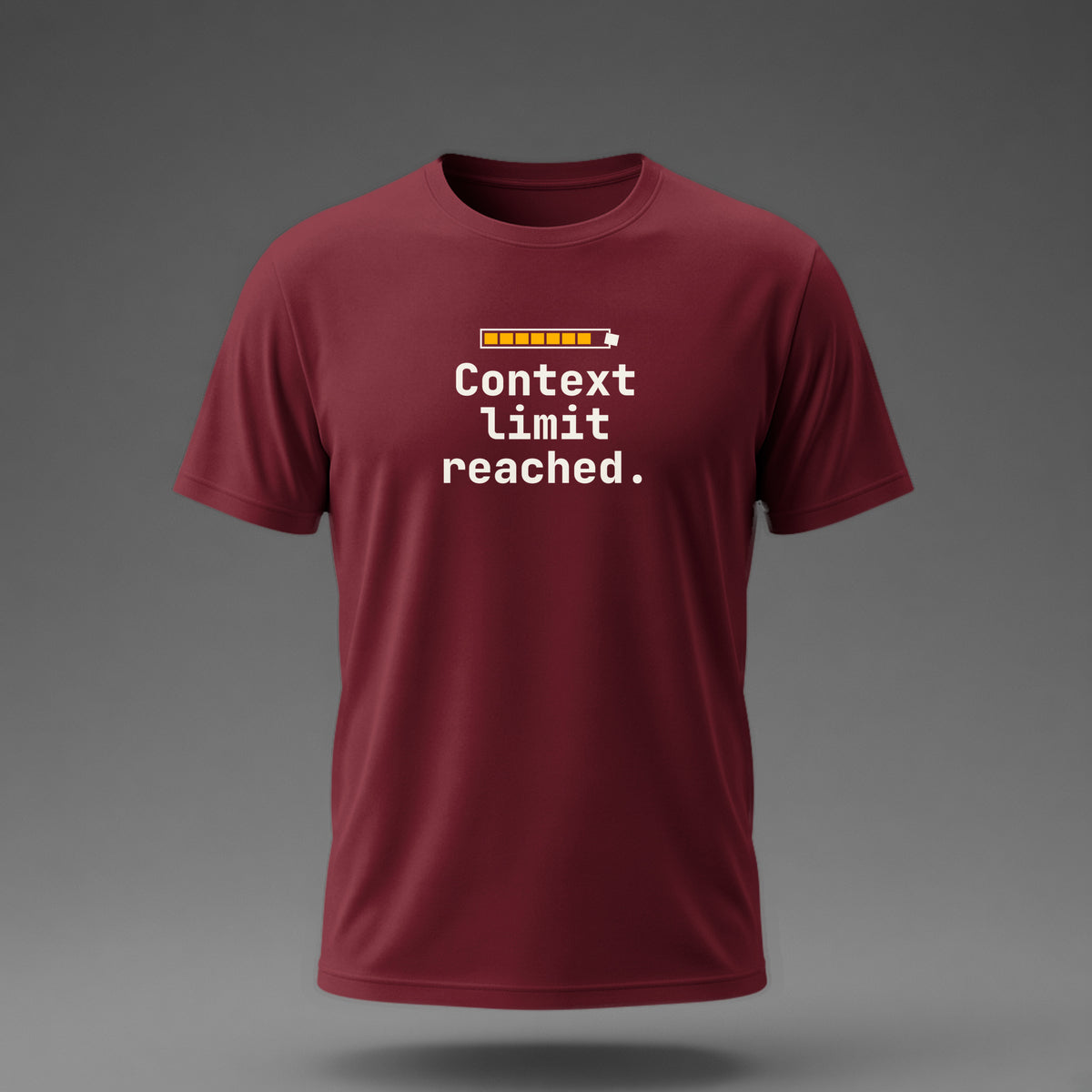 Front view: Maroon t-shirt floating on a grey background with 'Context limit reached.' under a usage meter whose last block bursts out of the frame printed across the chest in off-white and amber.