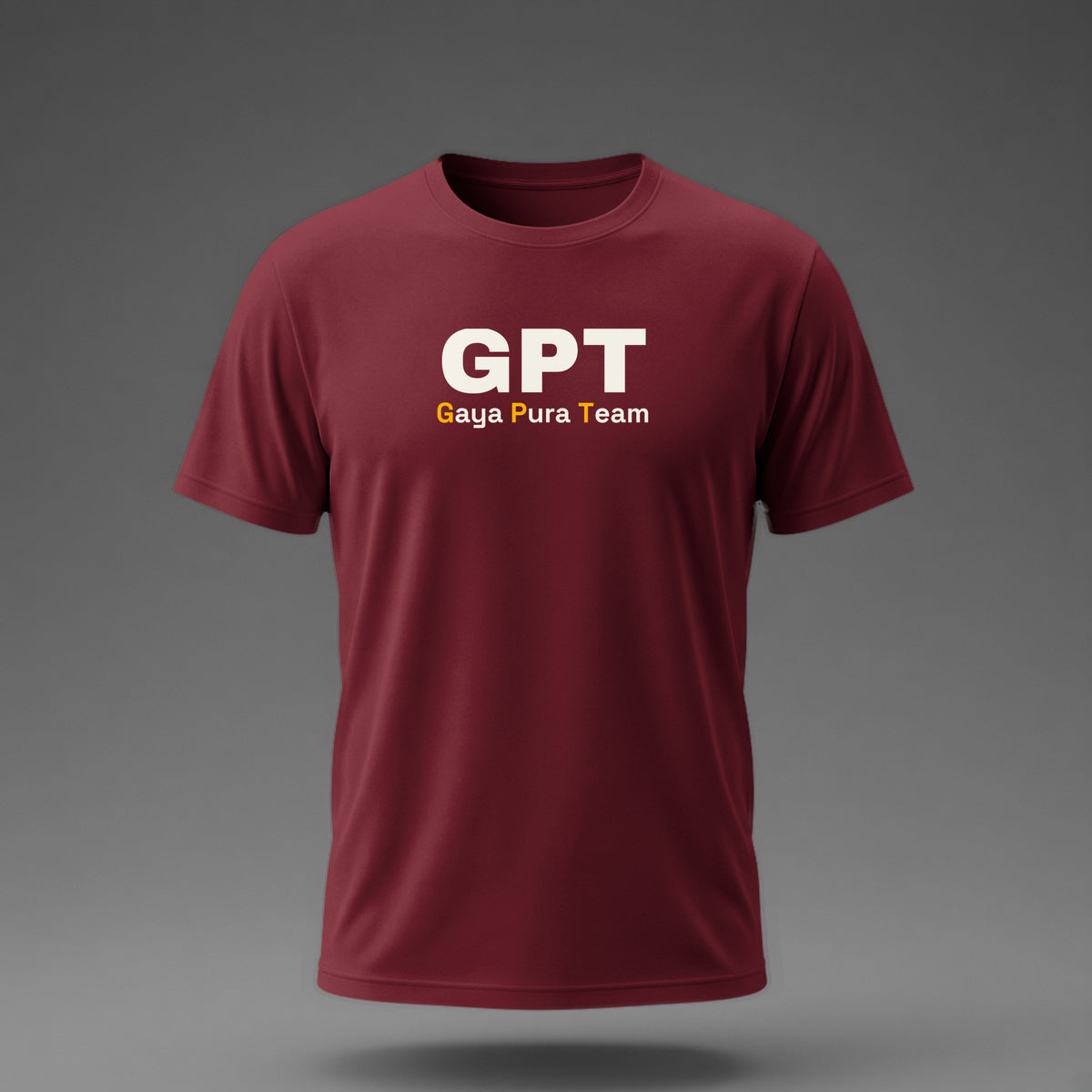 Front view: Maroon t-shirt floating on a grey background with a large three-letter acronym over the words 'Gaya Pura Team' printed across the chest in off-white and amber.